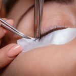 Close up of a beautician applying extended eyelashes to model.